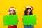Horizontal funny Christmas banner with two mixed race women with mouth and eyes wide open in surprised expression holding green