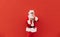 Horizontal half-length portrait of a positive Santa Claus touching his glasses, holding one cookie in his hand and a plate of