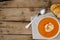 Horizontal image of bowl of tomato soup with spoon and toast on wood, copy space