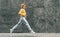 Horizontal image of cheerful young woman wearing yellow sweater, blue hight waist jeans, jumping high, feeling happy on the city