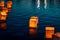 Horizontal image of several lanterns floating on water at dark during festival in Austin, Texas