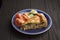 Horizontal image of vegetable pie with spinach and salmon on blue plate from above on a textured black background