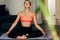 Horizontal indoor image of fitness woman sitting in yoga pose at home. Caucasian female in sportswear doing meditation on the