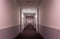 Horizontal interior view of the hallway of a modern apartment building; with sconces, doorways, molding, lighting  and carpeting