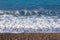 Horizontal line of wave on pebble beach on sunny day