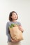 Horizontal orientation color image of a woman holding a paper bag overflowing with vegetables / Adding Veggies to your Diet