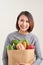Horizontal orientation color image of a woman holding a paper bag overflowing with vegetables. Adding Veggies to your Diet