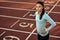 Horizontal outdoor image of young woman athlete posing on racetrack at stadium. Portrait of beautiful professional sportswoman