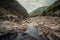 Horizontal outdoors shot of tiny pond in rocks under cloudy sky.