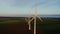 Horizontal panning from a drone, view of a massive wind farm among green fields