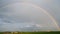 Horizontal panorama. Rural landscape, rain clouds and rainbow.