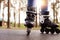 Horizontal photo of modern black roller skates being on road outskirts, unknown person riding during weekends, enjoying leisure