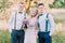 The horizontal photo of the two modern-dressed best men and the bridesmaid with the pink bouquet at the background of