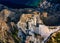 Horizontal photo with view down on rocky reef with blue sea around. Reef is under acropolis in Rhodos town Lindos