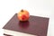 In the horizontal photo on a white background on the book is a fresh pomegranate