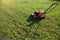 Horizontal photograph of a red-and-black mowers, which stands on the mowed half the lawn