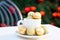 Horizontal picture of coffee cup with golden Christmas balls inside and around. Coffee pair on white table angle, grey