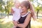 Horizontal portrait against a nature background of a cheerful twenty five year old woman with one year old daughter in her arms