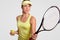 Horizontal portrait of pretty professional female tennis player holds racquet, ready to make favourite shot, holds ball, poses aga