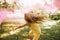 Horizontal rear view image of beautiful little girl with long blonde hair, playing in the park with magical pink dust for fairy