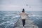 Horizontal rear view image of young woman with open arms looking to the ocean enjoying the journey. Pretty female watching flying