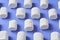 Horizontal rows of white marshmallows cylindrical form lies on purple scratched concrete table
