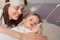 Horizontal shot of attractive happy cheerful mother with her cute baby lying on bed, family wake up in the morning, woman looking