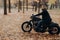 Horizontal shot of bearded biker in action or movement against park during autumn time, going to reach destination quickly, wears