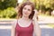 Horizontal shot of beautiful young woman having rest at park on summer day, . foxy haired female looking aside with dreamy facial