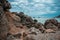 Horizontal shot of coastline full of rocks, some ships in the sea and the cloudy sky