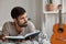 Horizontal shot of contemplative Caucasian guy with dark bristle, wears casual clothes, lies on bed with book, feels