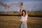 Horizontal shot of a female posing with a smoke bomb on a background of fields and windmills