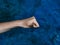 Horizontal shot of a fist with an open thumb pointing at the camera on a marbled blue background