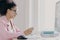 Horizontal shot of focused curly haired female office worker holds mobile phone, searches information in internet, wears optical