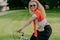 Horizontal shot of happy curly woman rides bike, keeps hands on handlebars, looks active and refreshed, dressed casually, wears