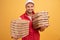 Horizontal shot of happy man holds two piles of carton boxes with pizza, has surprised joyful expression, works as courier in