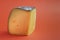 Horizontal shot of hard yellow cheese on a plain orange background