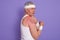 Horizontal shot of injured senior man posing sideways, mature male with white head band, elderly sportrsman posing isolated over