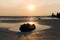 Horizontal shot of a large contrast silhouette of a stone against the background of a Sunny sunset, the sea and the sandy beach.