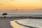 Horizontal shot of the mesmerizing view of the beach and sea, with umbrella and chairs at sunset