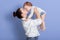 Horizontal shot of mom throws baby and kiss his, playing together and having fun, mother wearing white shirt and jeans, infant