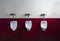 Horizontal shot of three urinals on a red and white wall