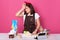 Horizontal shot of tired exhausted housewife being at kitchen, closing her eyes, touching her forehead with hand, wearing white t