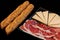 Horizontal shot of two baguettes and a plate of cheese and ham on the black background