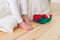 Horizontal shot of unrecognizable little small child stands on wooden floor with elf s shoes, sits on white bedclothes