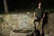 Horizontal shot of a young sporty male standing next to an old stone source of drinking water