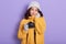 Horizontal studio shot of magnetic sweet pretty amateur photographer wearing yellow sweater, grey gloves and hat, holding