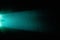 Horizontal turquoise scattered light beam against a dark background in a black dot