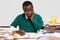 Horizontal view of amazed black male works with documents, writes down notes in notepad, has stupefied facial