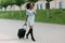 Horizontal view of the cheerful afro-american girl holding the luggage while talking using the mobile phone.